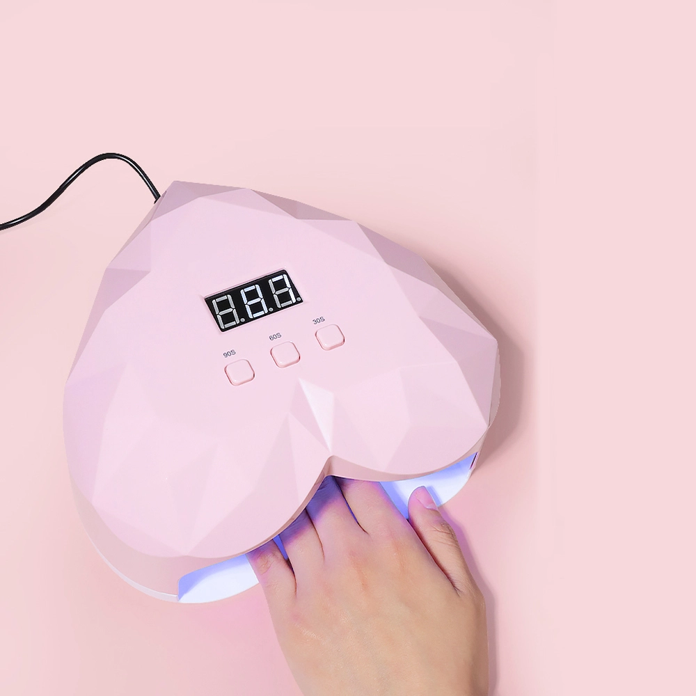 Lampada LED UV per unghie a forma di cuore, di color rosa.